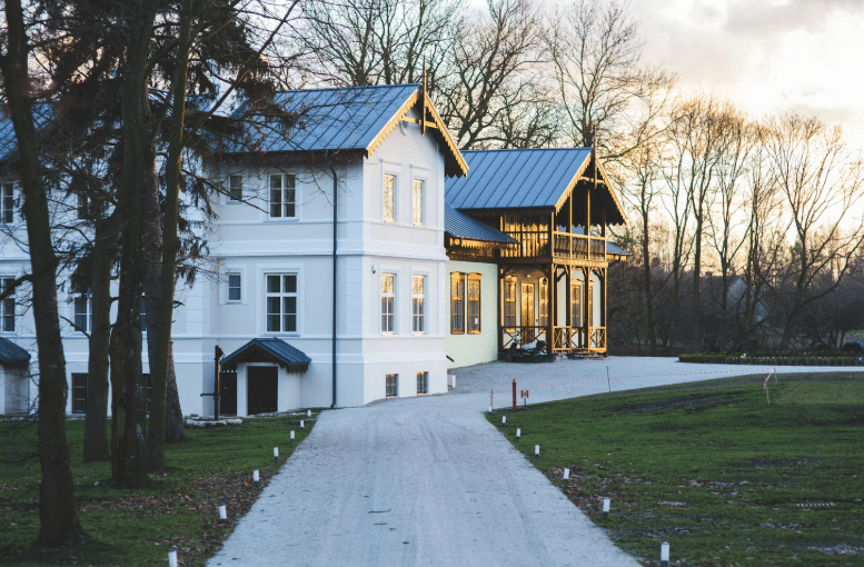 Large white and wood luxury house with driveway at sunset