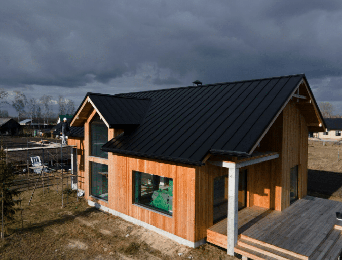 Wooden house under construction with black roof panels