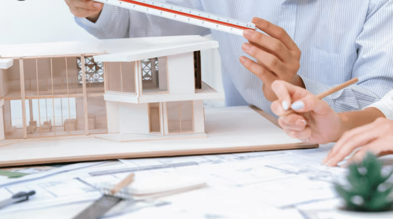 Designers measuring scale architectural model of a modern house