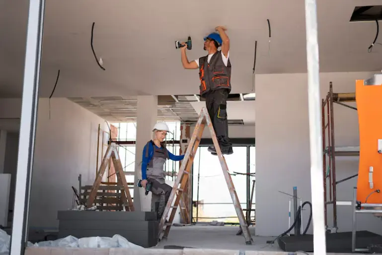 Construction workers installing ceiling systems inside a commercial building during an interior renovation project.