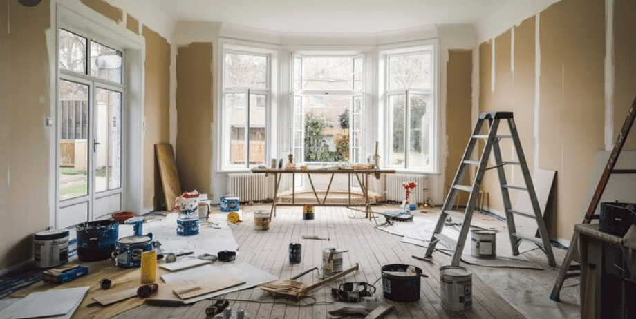 Residential interior renovation with construction tools, ladders, and unfinished wall framing.