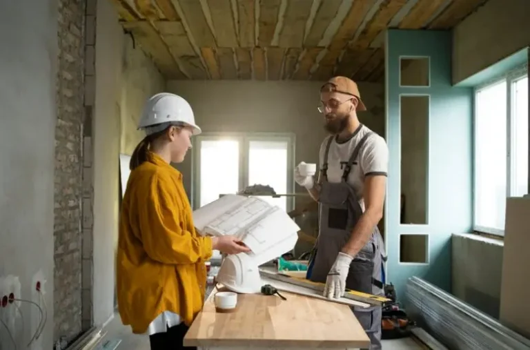 Contractor and project manager reviewing renovation plans on site