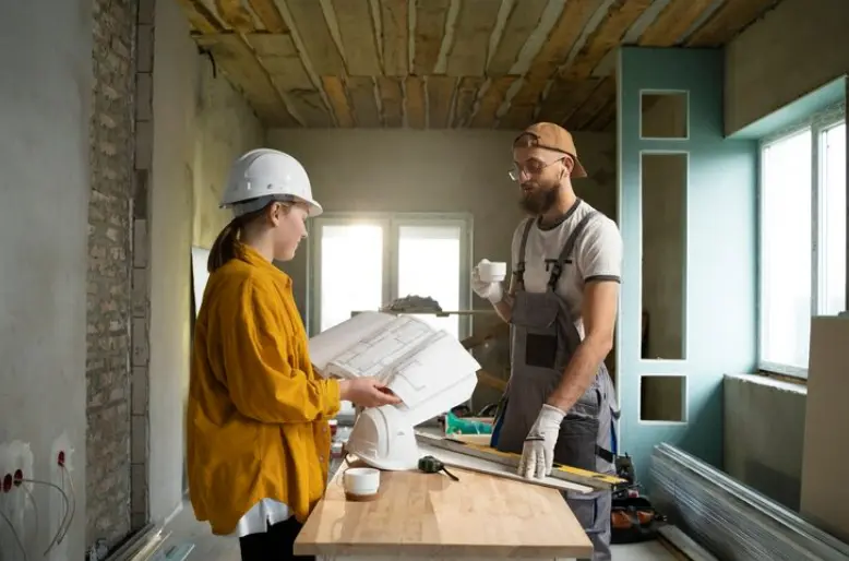 Contractor and project manager reviewing renovation plans inside a home under construction.