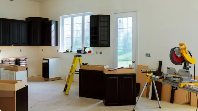 Kitchen renovation in progress with cabinet installation, construction tools, and remodeling equipment.