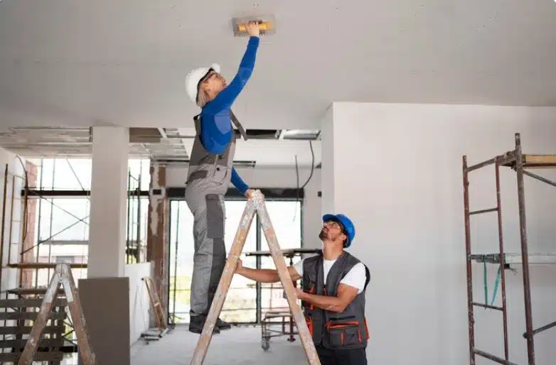 Construction workers finishing drywall ceiling installation inside a commercial renovation project.