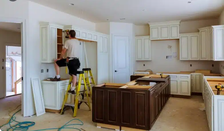 Contractor installing kitchen cabinets during a residential kitchen remodeling project.