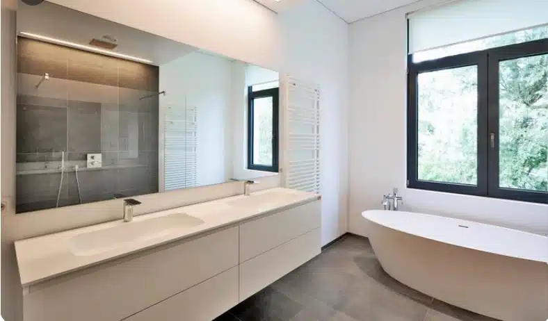 Modern bathroom renovation with double vanity, freestanding bathtub, large mirror, and walk-in shower.