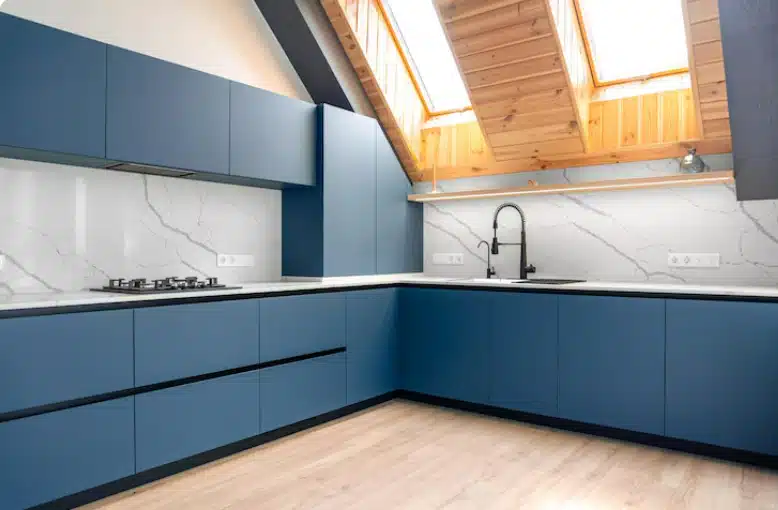 Contemporary kitchen with blue custom cabinets, marble-look backsplash, skylights, and modern fixtures.