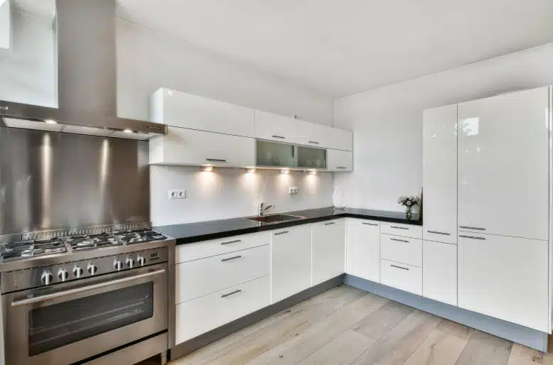 Modern white kitchen with sleek cabinetry, stainless steel appliances, and black countertops.