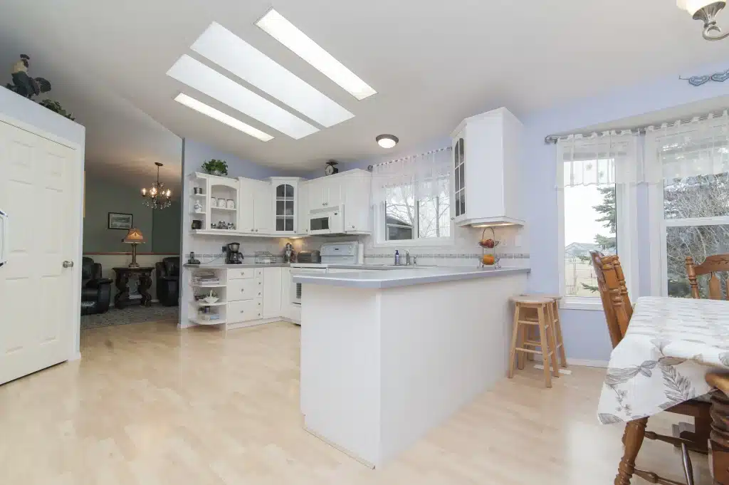 Bright traditional kitchen with white cabinetry, center island, and updated flooring after renovation.